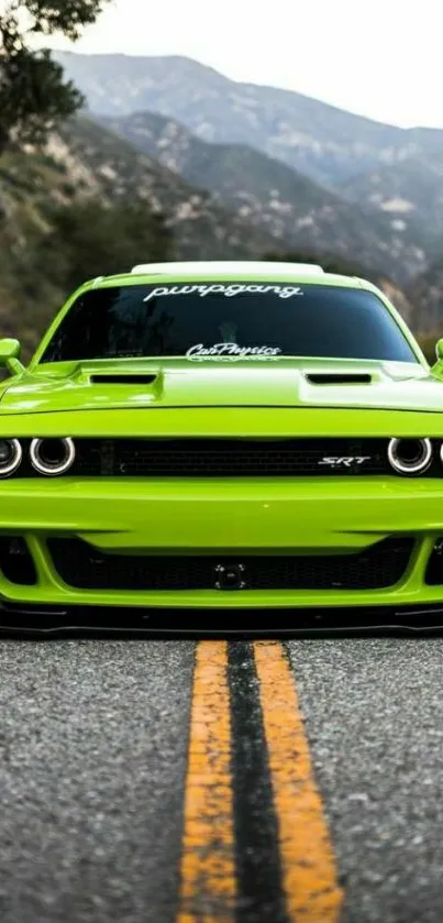 Green sports car on mountain road with scenic backdrop.