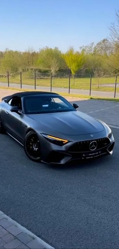 Sleek grey sports car parked on a road under a clear blue sky.