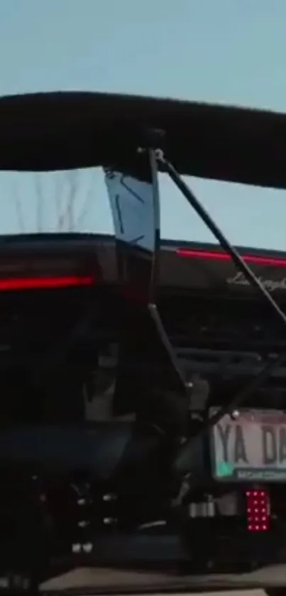 Lamborghini rear view under twilight sky, showcasing sleek design and red lights.