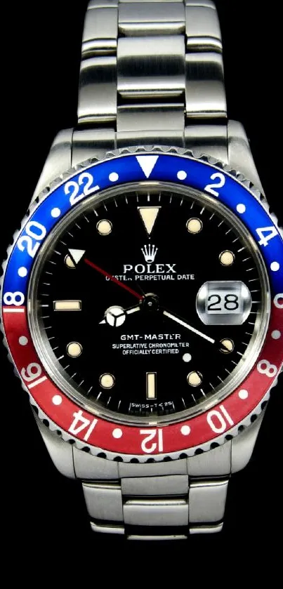 Luxury watch with red and blue bezel on black background.