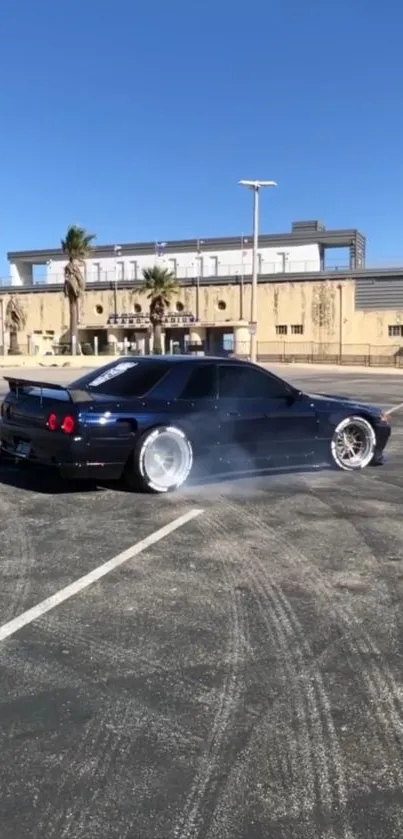 Drifting black sports car under a clear blue sky with palm trees in the background.