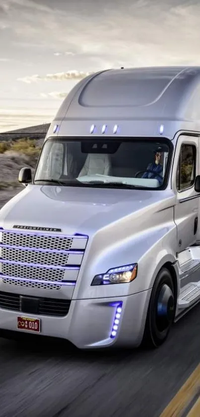 Sleek silver truck driving on a scenic highway at sunset.