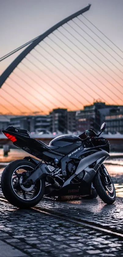 Black motorcycle by a bridge with sunset reflecting on water.