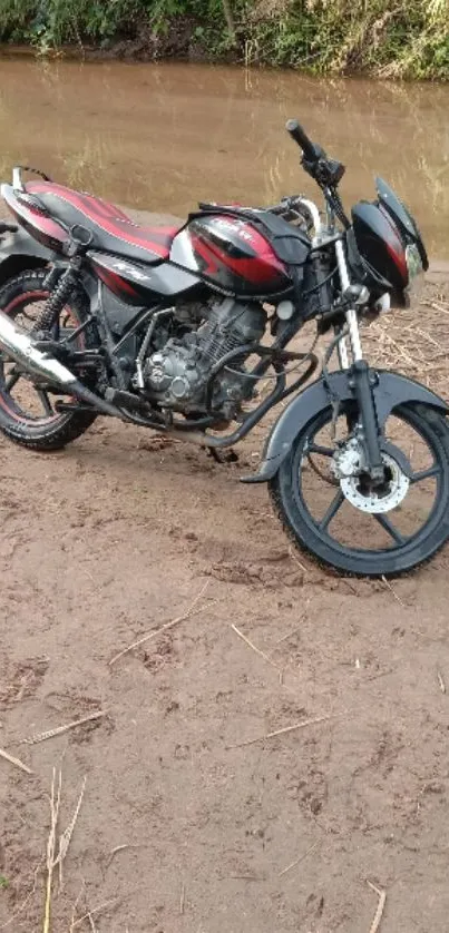 Motorcycle parked near a riverbank in nature.