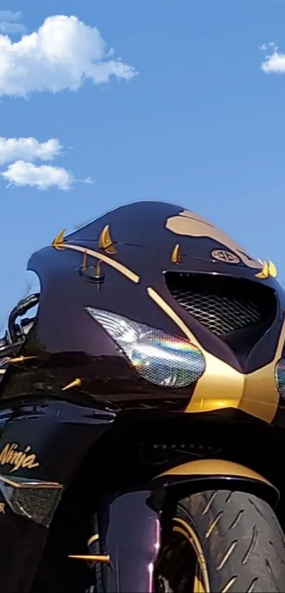 Sleek motorcycle against blue sky with white clouds.