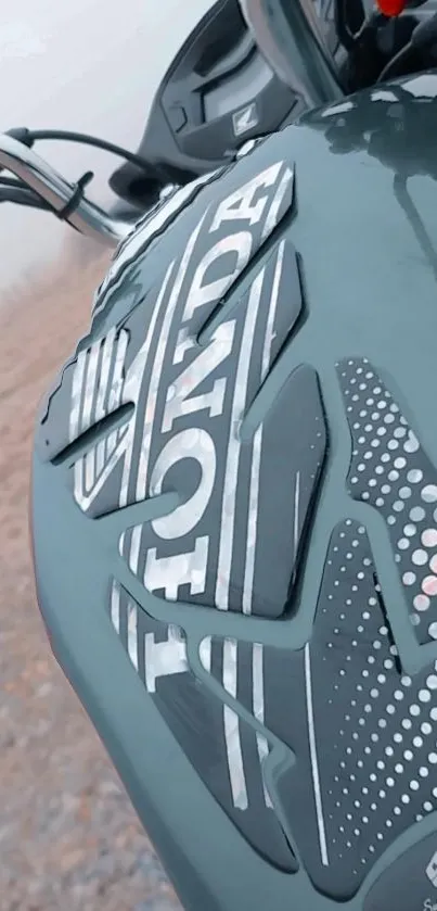 Close-up of a motorcycle fuel tank with intricate design in dark green.