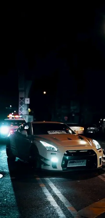 Sleek car driving on a dark street at night, illuminated by city lights.