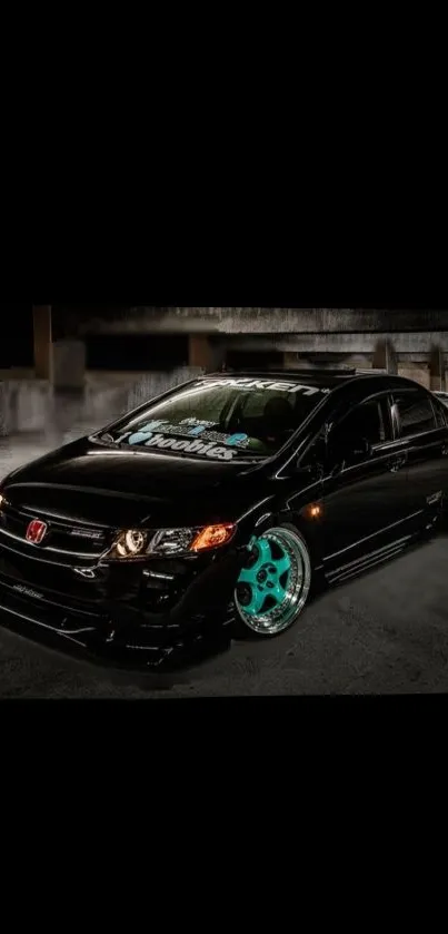 Black car with teal wheels in a night urban setting wallpaper.