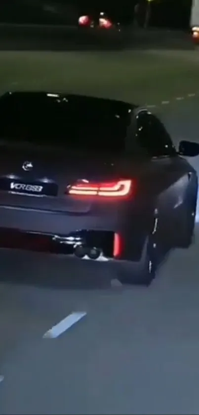 Sleek black car driving at night with glowing taillights.