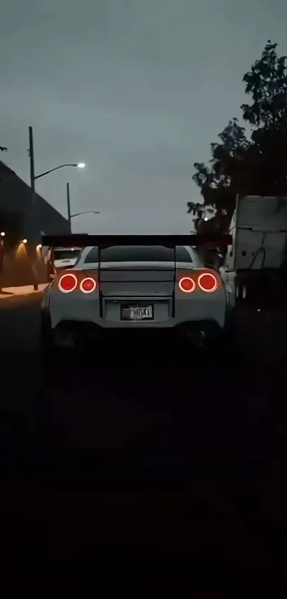 White sports car with glowing tail lights at night.