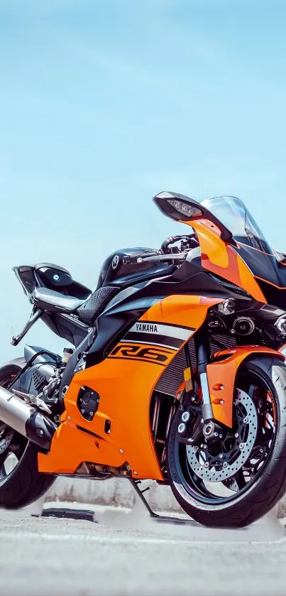 Sleek orange sport motorcycle against a clear sky.