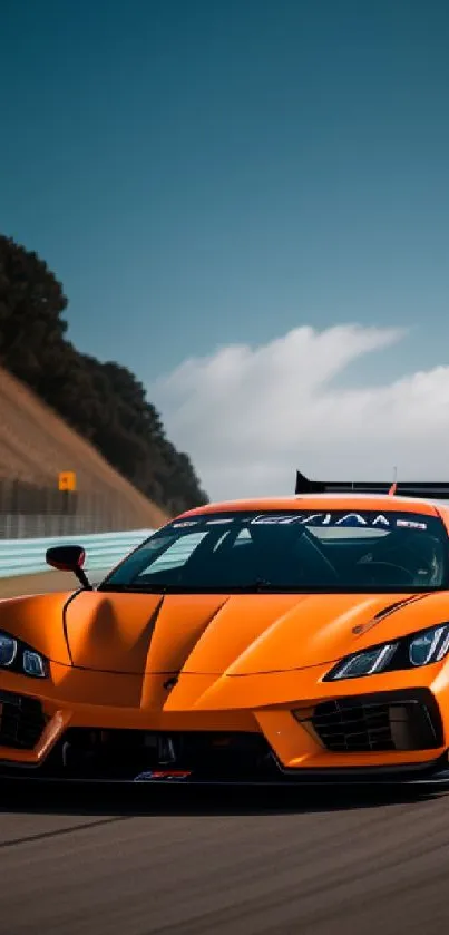 Orange sports car racing on a track with blue sky.