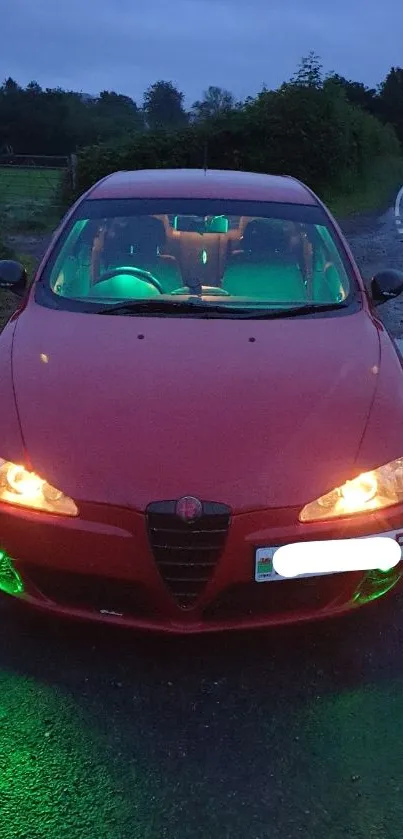 Red car with green lights on a nighttime road.