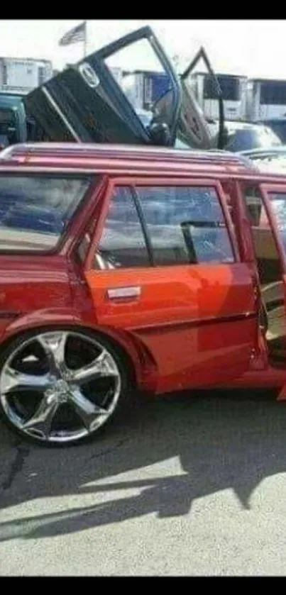 Sleek red car with chrome wheels and open doors in an urban setting.