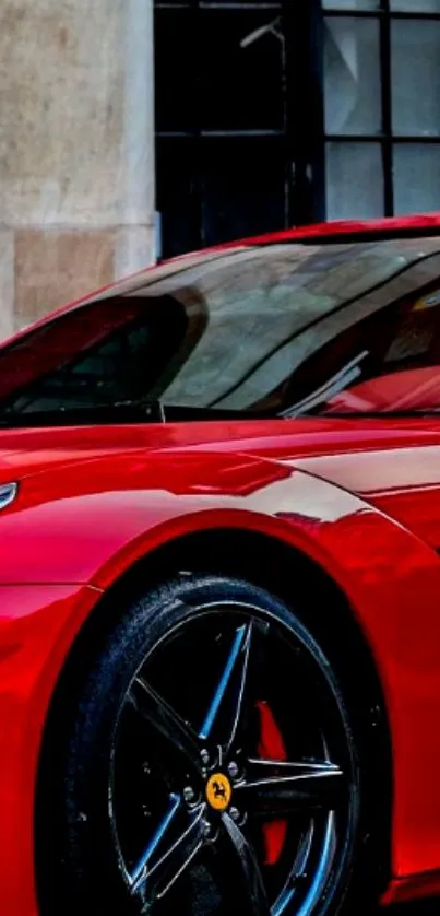 Sleek red sports car with shiny finish, showcased against an urban backdrop.