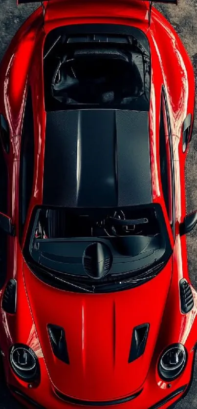 Top view of a sleek red sports car on a textured surface.