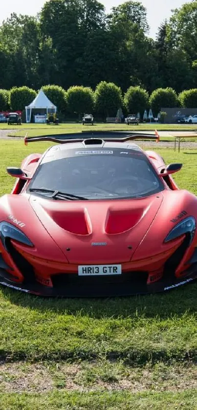 Sleek red supercar on green grass, perfect for mobile wallpaper.