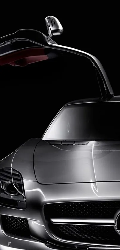 Sleek silver car with gullwing door open against a dark background.