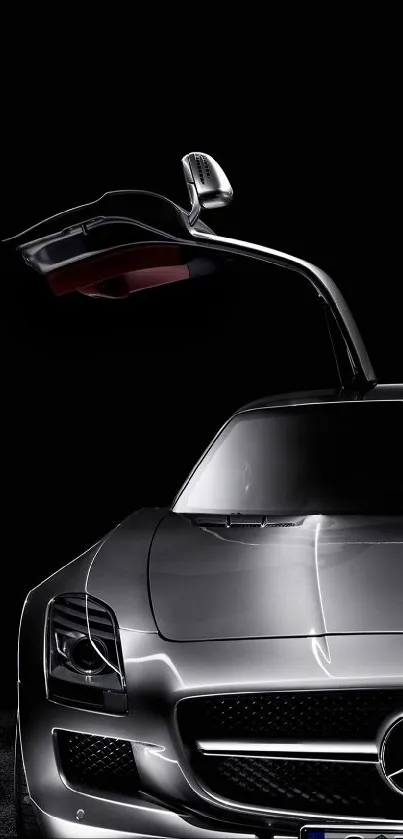 Sleek silver sports car with gullwing doors against black background.