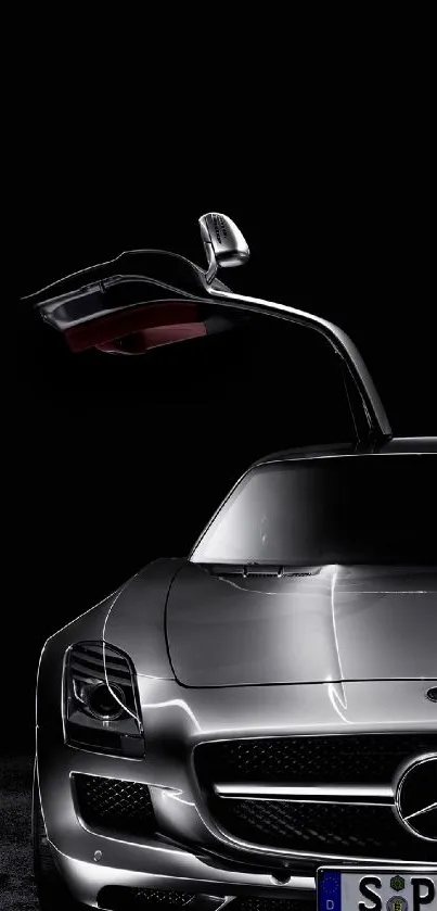 Sleek silver sports car with gullwing door on a black background.