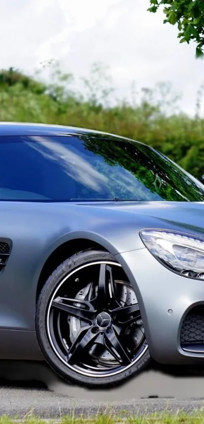 Sleek silver sports car with chrome wheels on an outdoor road scene.