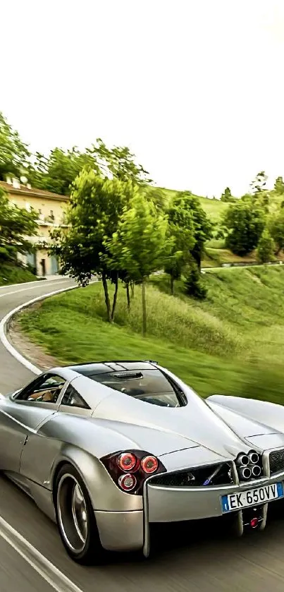 Silver supercar driving on a scenic countryside road.