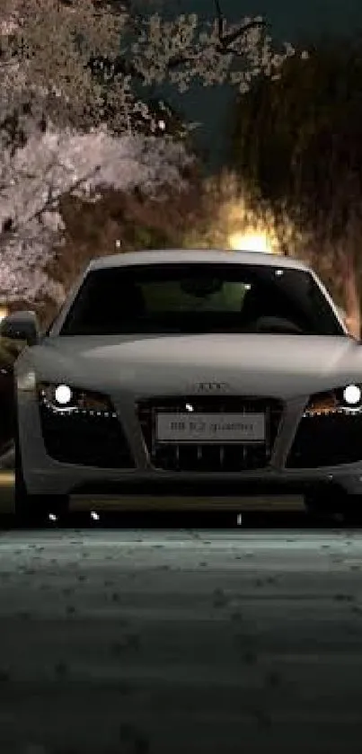 Sports car at night beside cherry blossoms, ideal for mobile wallpaper.