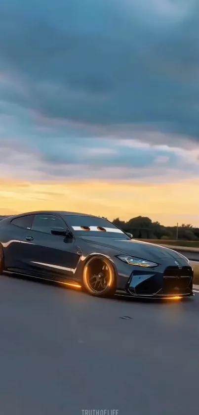 Sleek dark sports car on open road at sunset.