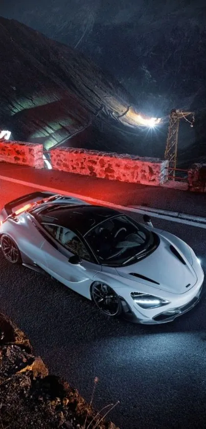 Sleek sports car driving on a mountain road at night.