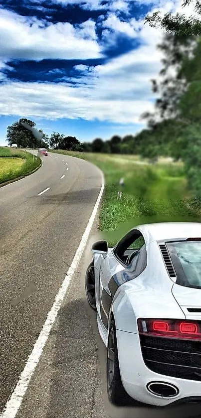 Sleek white sports car on a winding open road under a blue sky.