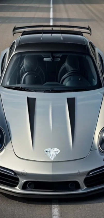 Sleek silver sports car with a diamond on the hood on an open road.