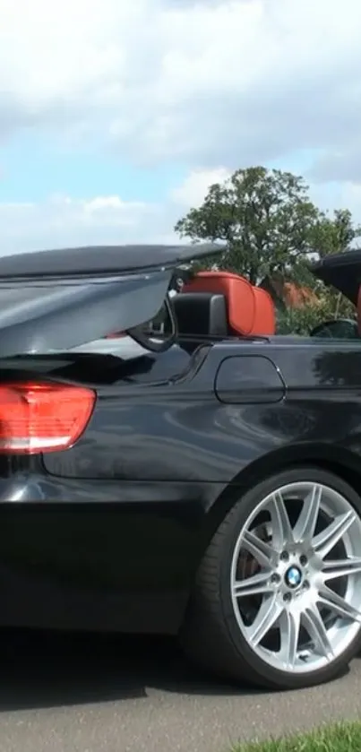 Black convertible sports car with red seats under a blue sky.