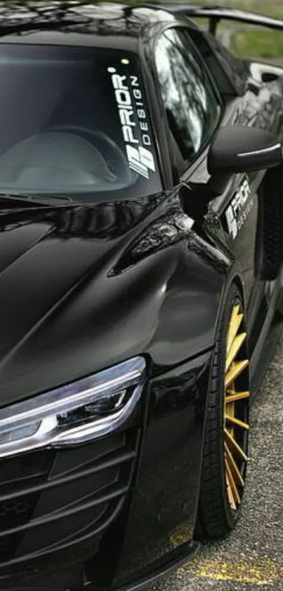 Sleek black sports car with golden rims parked on a street.