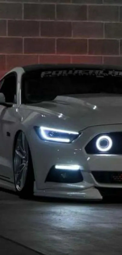 Sleek white sports car with glowing LED lights against a brick wall backdrop.