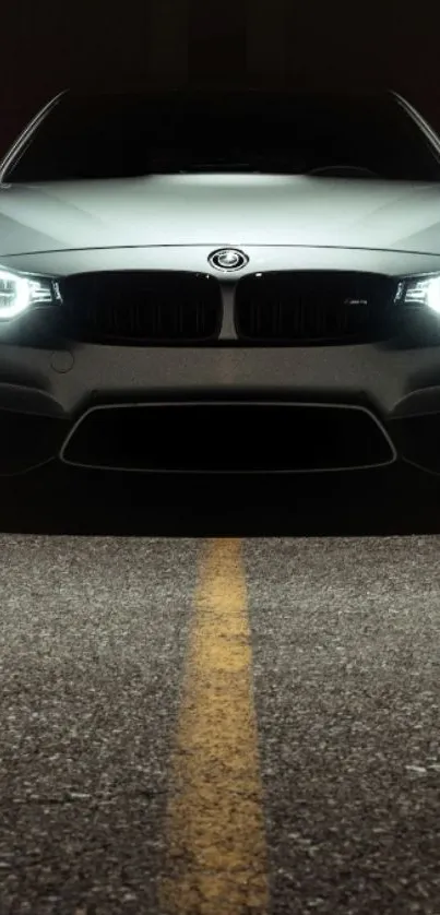 Elegant gray sports car with glowing headlights in the dark.