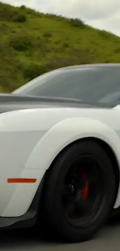 Sleek white sports car driving on a scenic road.