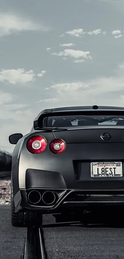 Gray sports car parked on a track with a cloudy sky.