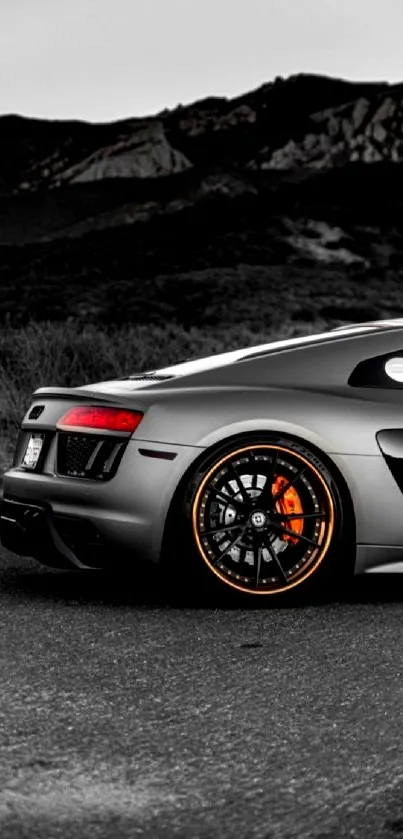 Sleek gray sports car with orange accents on a scenic road.