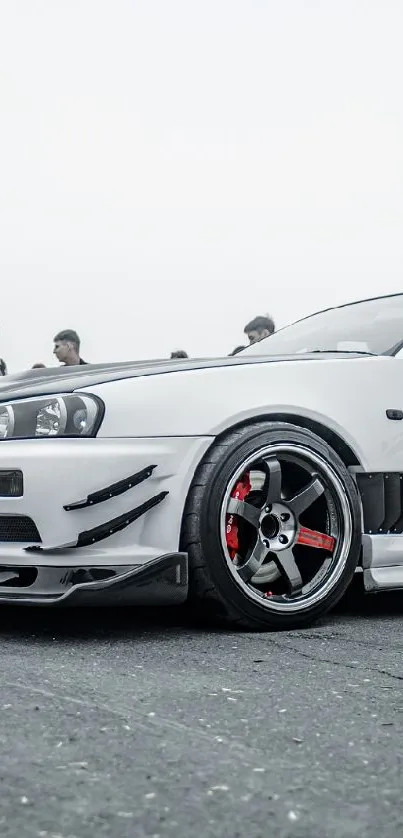 Sleek white sports car with red wheels on display.