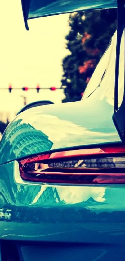 Teal sports car with rear wing on street, perfect for phone wallpaper.