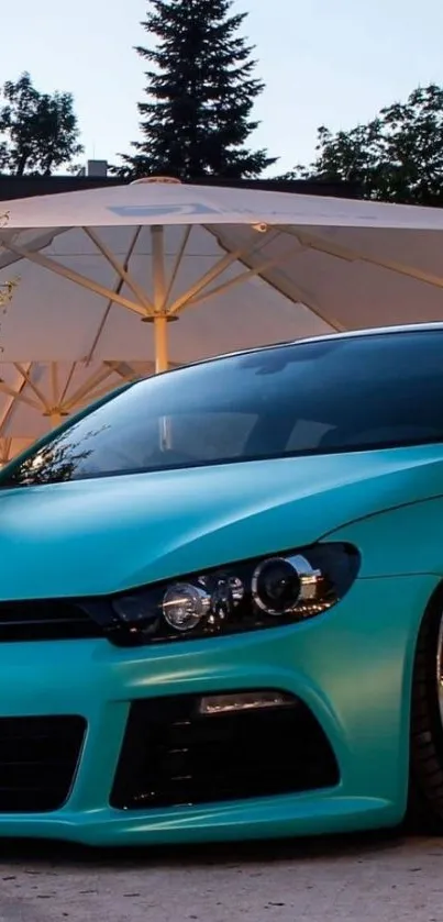 Turquoise car parked outdoors with trees in the background.