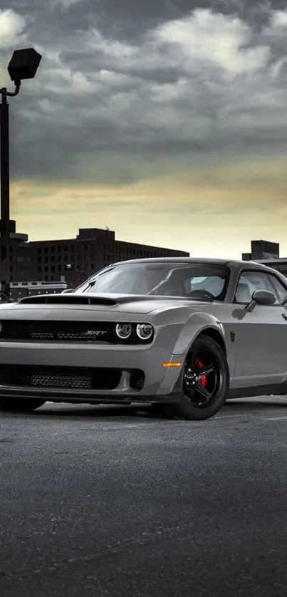 Gray sports car in urban setting with city skyline at dusk.