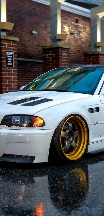 Sleek white car with gold rims in a rainy city street.