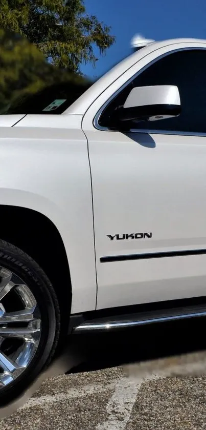 Sleek white car with chrome wheels under blue sky.