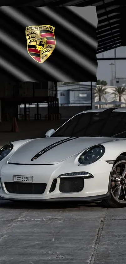 Sleek white Porsche in an industrial setting with logo backdrop.