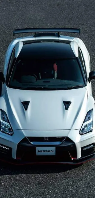 Top view of a sleek white sports car on a dark asphalt background.