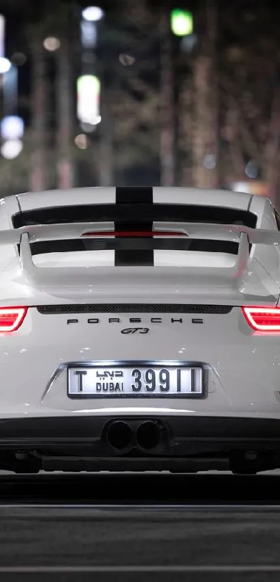 White sports car on city street at night, rear view.