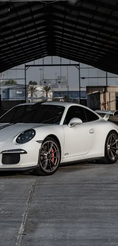 Sleek white sports car in industrial setting.