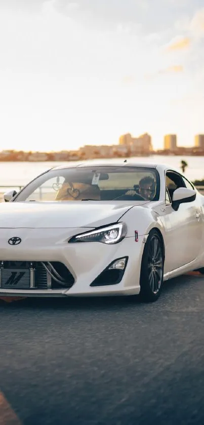 Sleek white sports car on urban road with cityscape backdrop.