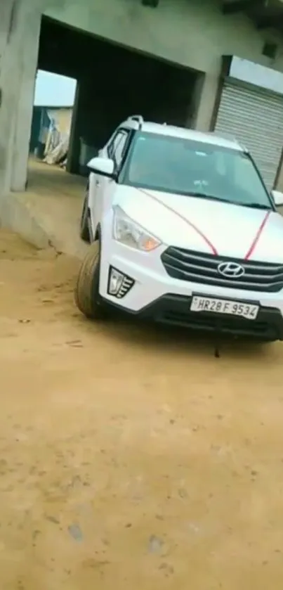 White SUV parked on sand near a garage.